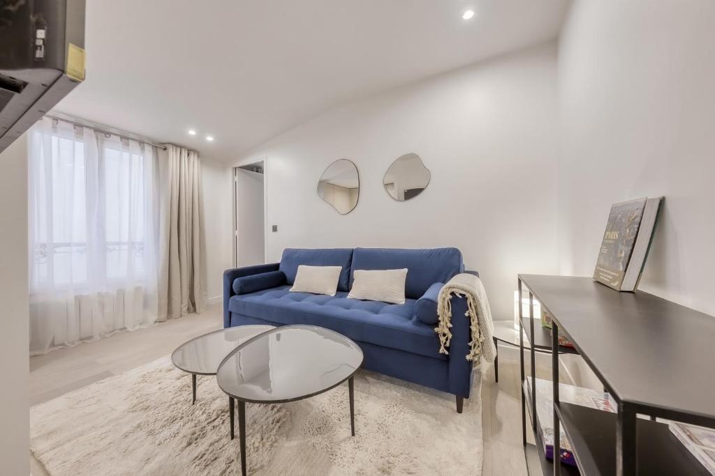 uma sala de estar com um sofá azul e uma mesa em 1 Bedroom near Le Bon Marché em Paris