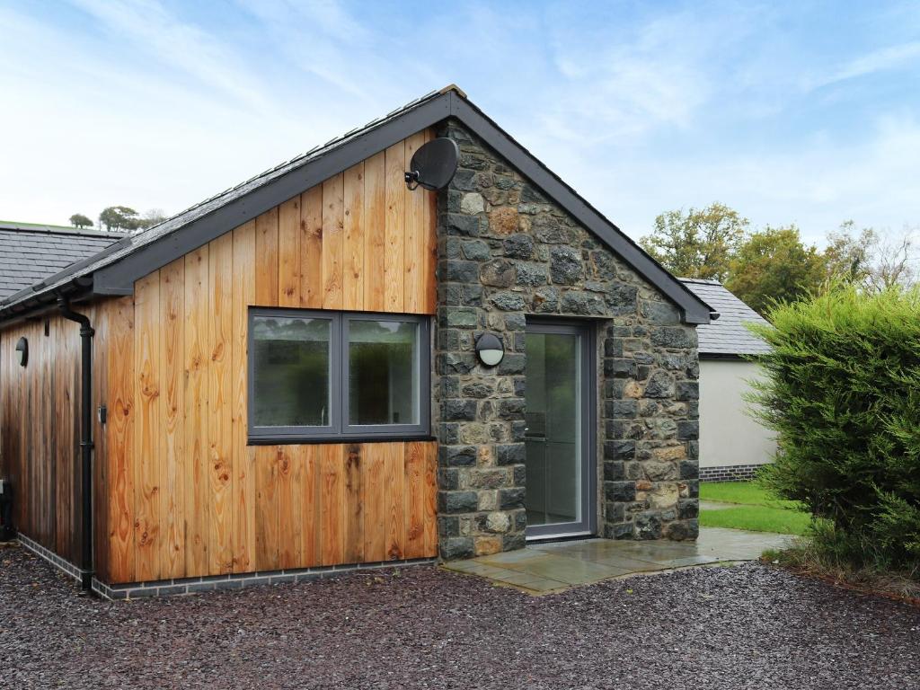 a wooden and stone house with a garage at Beudy Wern Goch in Llanuwchllyn