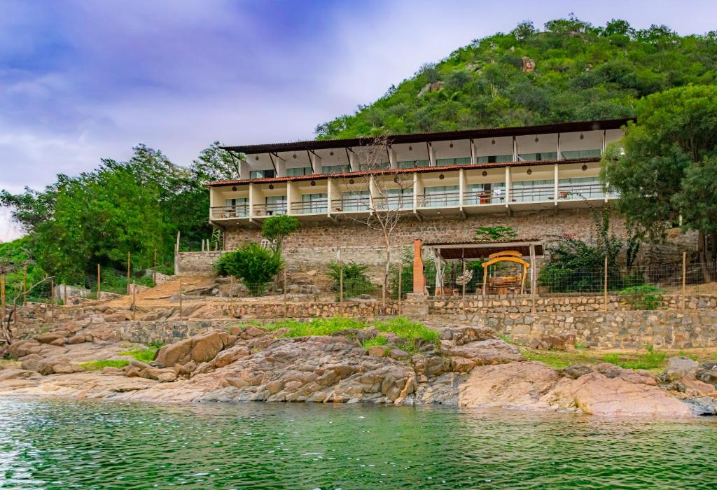 a building on a hill next to a body of water at Pousada Porto de Piranhas in Piranhas