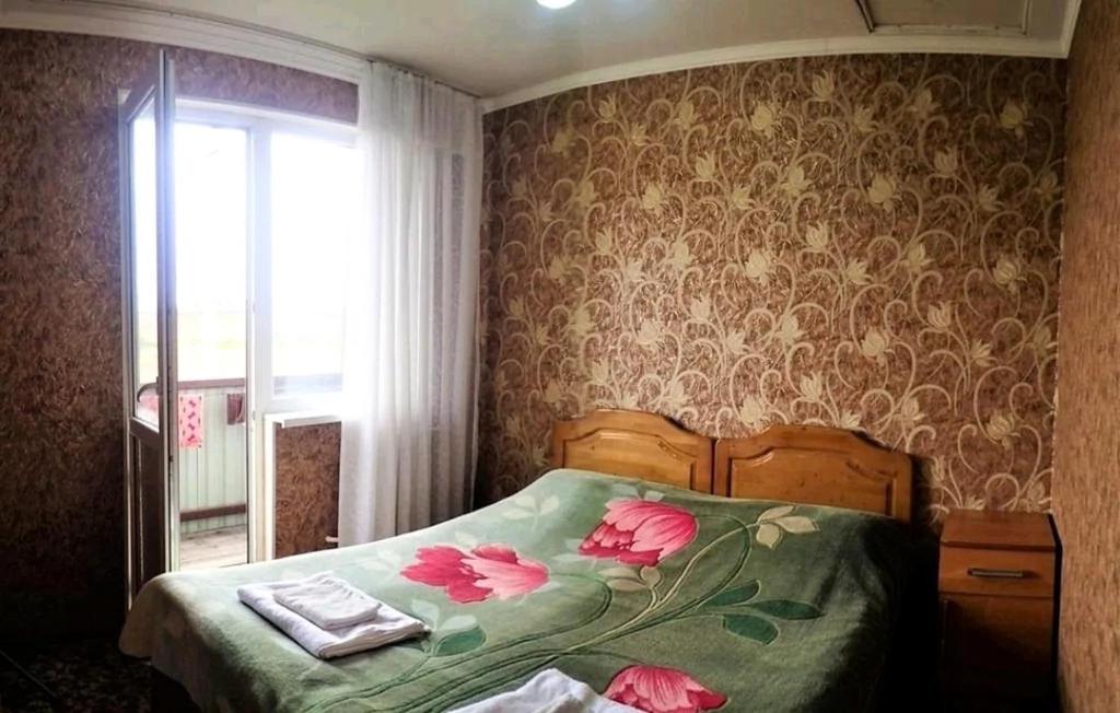 Un dormitorio con una cama con flores rosas. en Janat Family Guesthouse, en Karakol