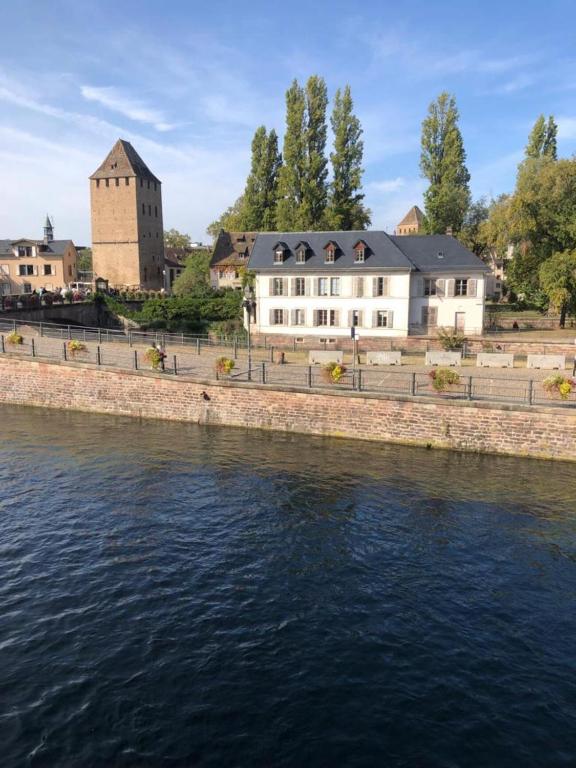 un grand bâtiment blanc à côté d'une rivière dans l'établissement Au bord de l’eau, à Strasbourg