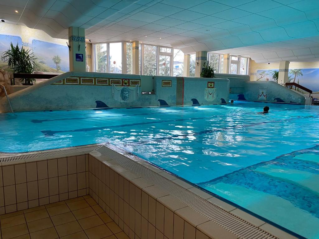 a large indoor swimming pool with blue water at FeWo Waldsee mit Pool und Sauna inklusive in Sankt Englmar