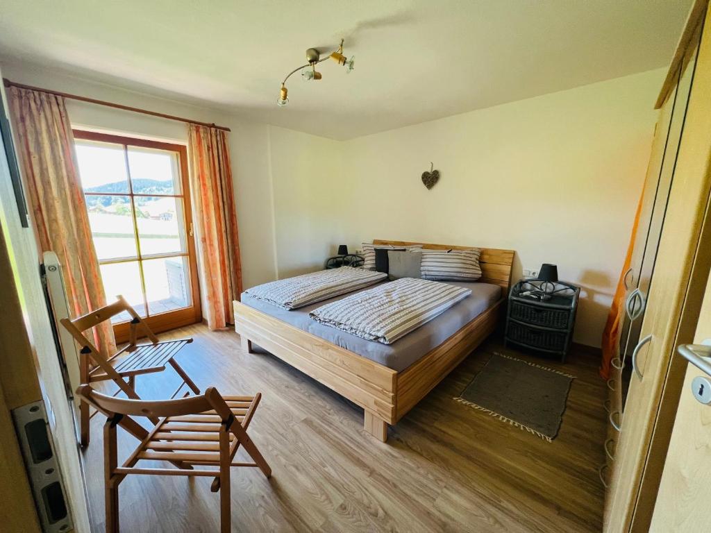 een slaapkamer met een bed, een stoel en een raam bij Ferienwohnungen Britta Heim in Oberstaufen