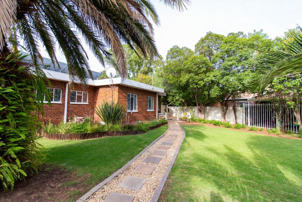 a brick house with a grassy yard next to a building at Gastehuis 17 in Bloemfontein