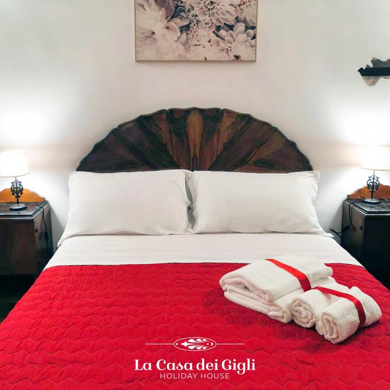 een bed met twee handdoeken op een rode deken bij La Casa dei Gigli in Lecce