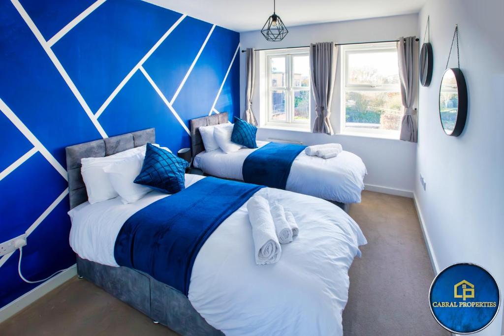 two beds in a room with blue walls at Can accommodate up to 7 people , 3Bed House in Reading by Cabralproperties - free parking, Netflix in Reading