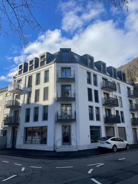 um edifício branco com um carro estacionado em frente em Modern City Apartment em Interlaken