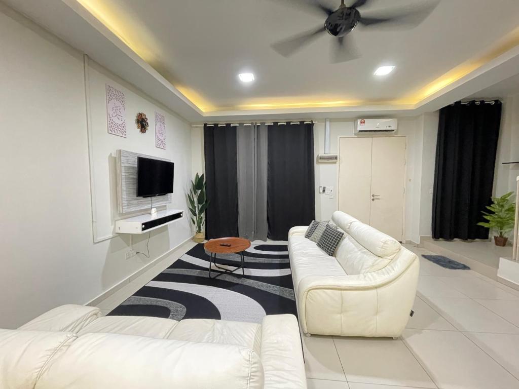 ein Wohnzimmer mit einem weißen Sofa und einem TV in der Unterkunft HANZ HOMESTAY MELAKA - MUSLIM HOMESTAY UNIT 3 in Malakka