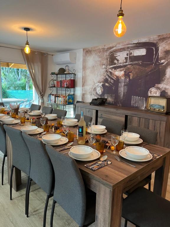une grande table en bois avec des chaises et des assiettes. dans l'établissement la grande Vadrouille, à La Salvetat-sur-Agout