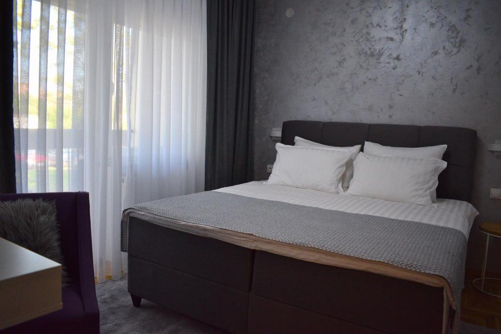 a bedroom with a large bed with white pillows at BorLu apartman in Đakovo