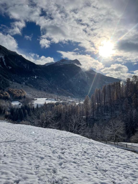 una colina cubierta de nieve con el sol en el fondo en Wohnung gemütlich mit Stil „la tgea cotschna“ en Pignieu