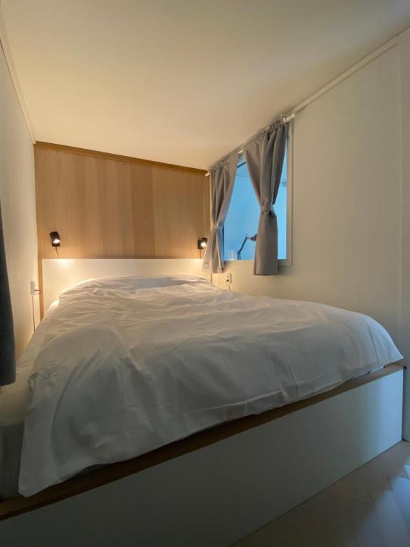 une chambre avec un grand lit blanc avec une fenêtre dans l'établissement Entire renovated apartment from 1780 with Kitchen, Bath, Bedroom, and Living Room in Skuteviken, à Bergen