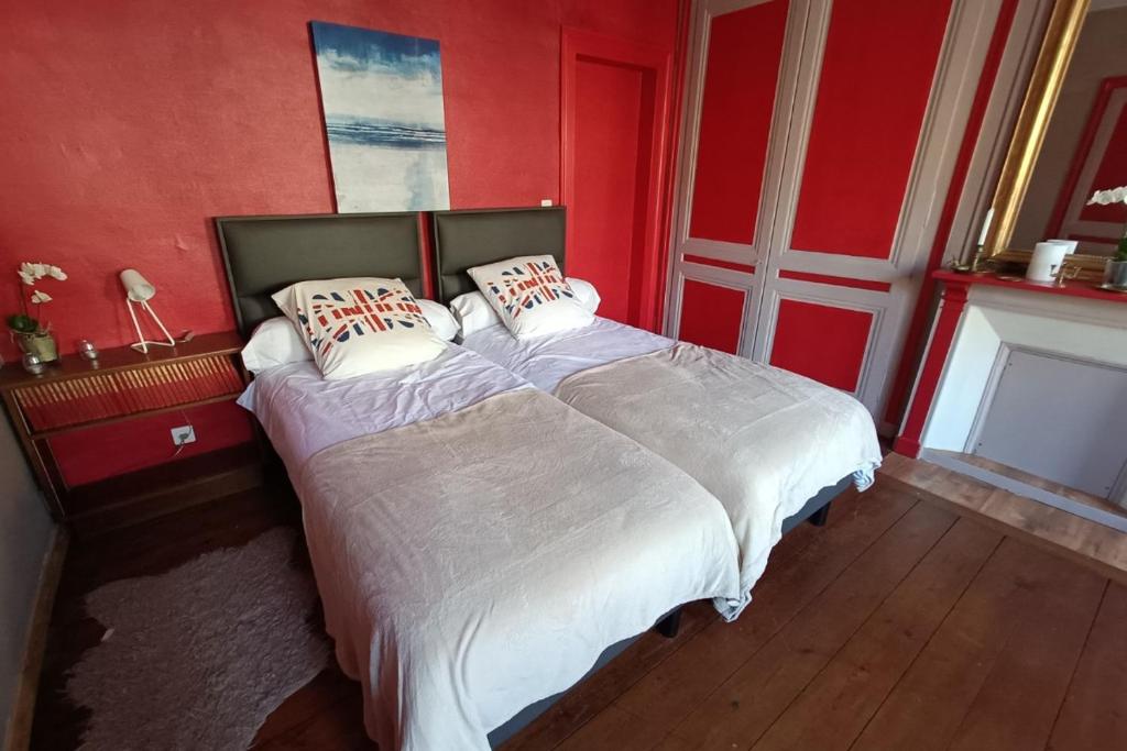 a bedroom with a large bed with red walls at Chambre Etretat in Fécamp