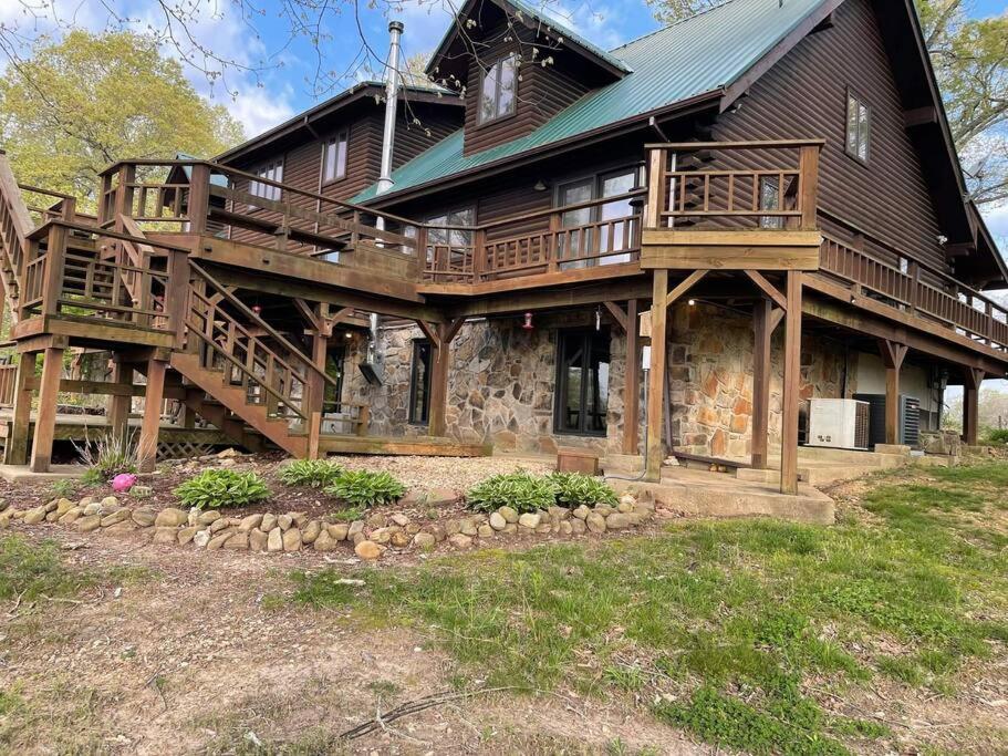 une grande maison en bois avec une grande terrasse dans l'établissement Buffalo River Lodge (Yellville)- Lower Level, à Saint Joe