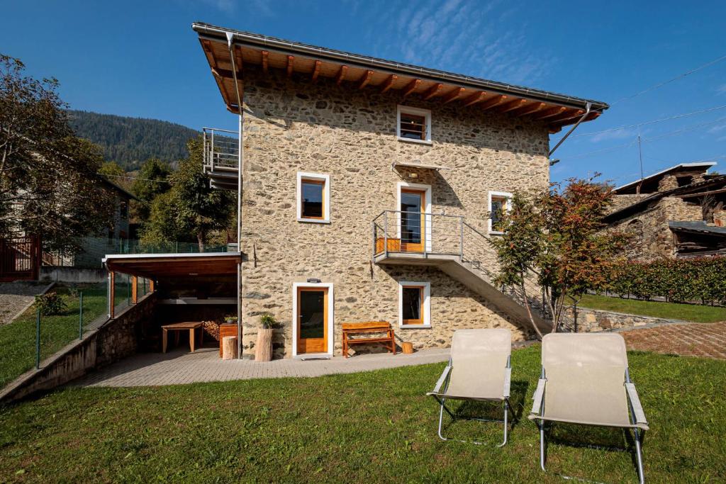 a stone house with two chairs in the yard at REVO Apartments - Cà Berti in Teglio