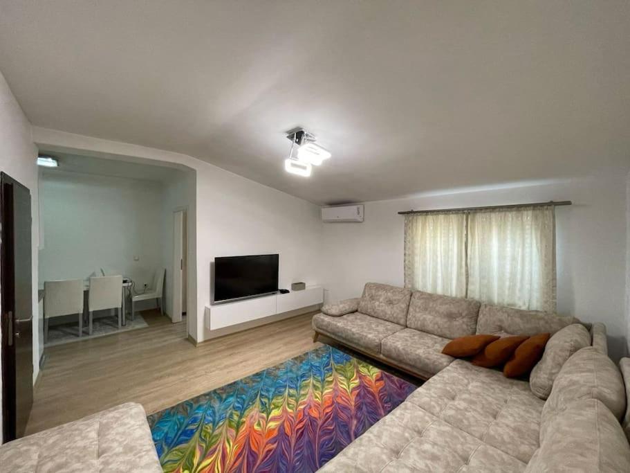 een woonkamer met een bank en een flatscreen-tv bij Central City Apartment in Pristina