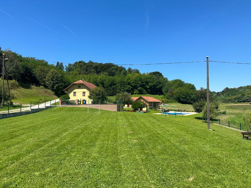 a large grass field with a house in the background at Ruralna kuca 'Villa Zagorka' za odmor sa bazenom i bočalištem in Donja Pačetina