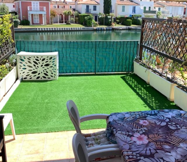 uma varanda com um quintal de relva verde em Appartement rue de l'amarrage à PORT GRIMAUD avec Terrasse vue canaux et garage em Grimaud