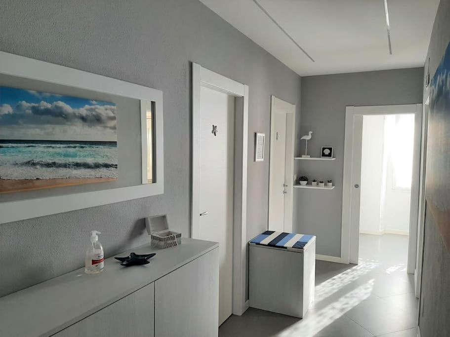 een badkamer met een wit aanrecht en een foto van de oceaan bij Aleph Guest House relax a due passi dal mare in Fertilia