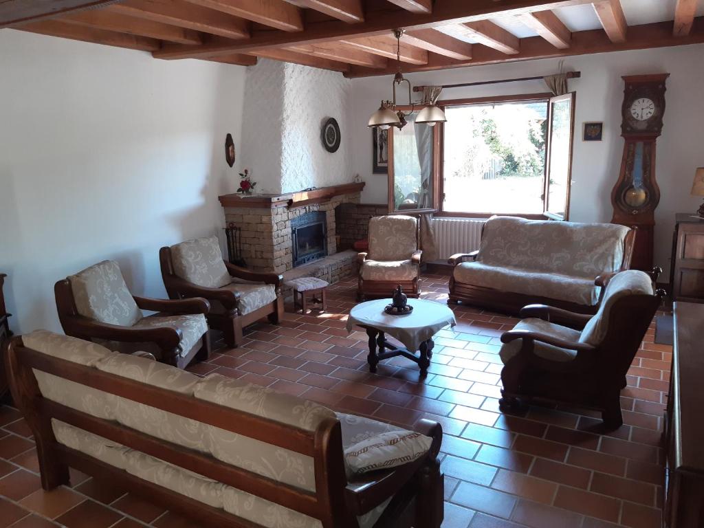ein Wohnzimmer mit einem Sofa, Stühlen und einem Kamin in der Unterkunft Le Gîte des Petits Cailloux 