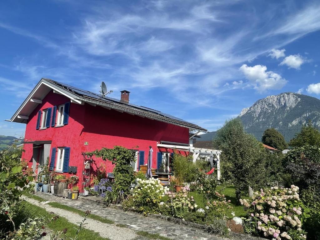 a red house with a mountain in the background at Ferienwohnung Seidenhuhn in Kiefersfelden