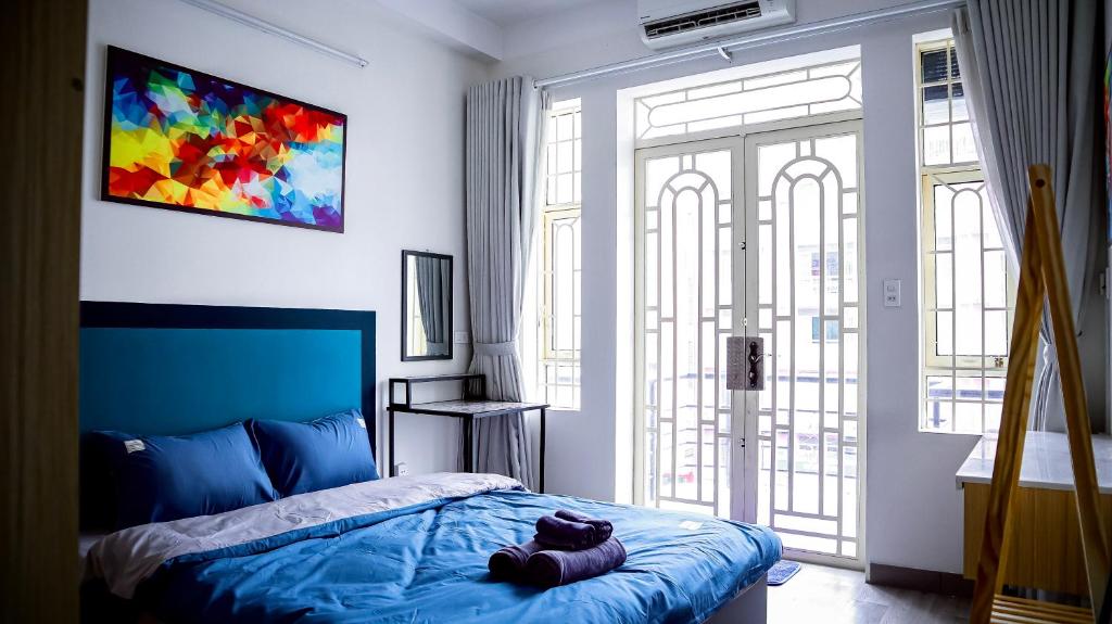 een slaapkamer met een blauw bed en een groot raam bij La Vie - Saigon Homestay Cafe & Tea in Ho Chi Minh-stad