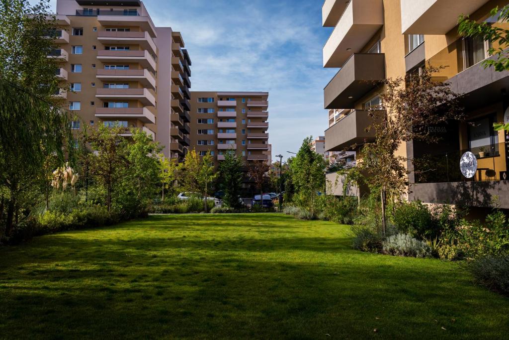 um jardim relvado entre dois edifícios altos em JAD - Luxury - 3 Room Apartments - Urban Plaza em Braşov