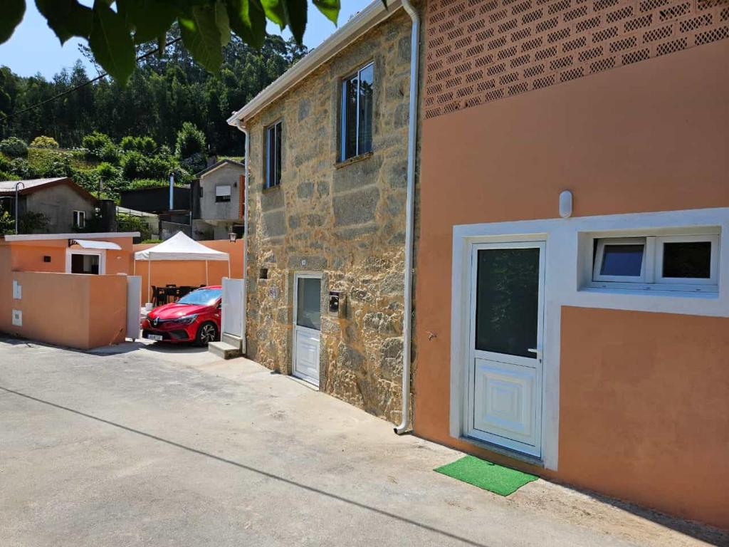 Ein rotes Auto parkte neben einem Gebäude mit einer Tür in der Unterkunft Casasoutelo in Carrazedo