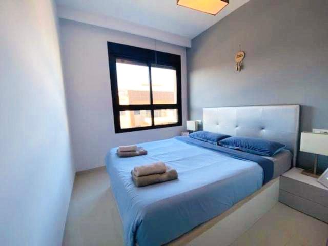 La HoradadaにあるAppartement Mil palmerasのベッドルーム1室(大型ブルーベッド1台、タオル付)
