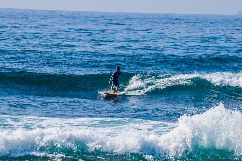 a person riding a wave on a surfboard in the ocean at Chill River Villa - Villa with Scenic River Views in Weligama
