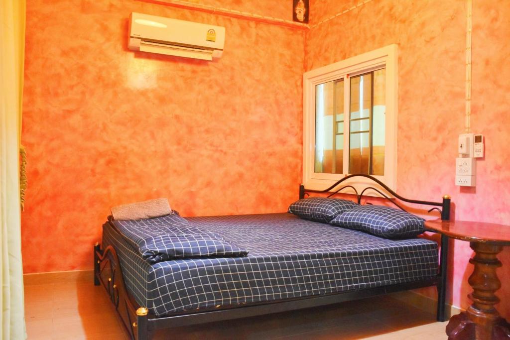 Ce lit se trouve dans un dortoir doté d'une table et d'une fenêtre. dans l'établissement รีสอร์ทบ้านพระร่วง พระปรางค์ ศรีสัชนาลัย, 