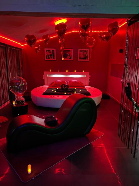 um quarto vermelho com uma cama e um sofá preto em Loft d'amour em Ligné