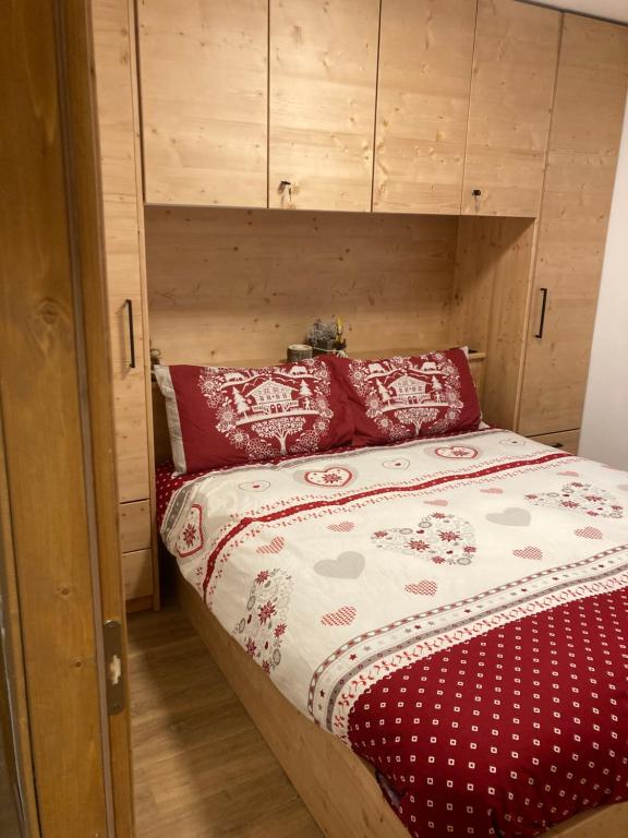 un letto con testiera in legno e cuscini rossi di La Casina sul Brenta - Madonna di Campiglio a Madonna di Campiglio