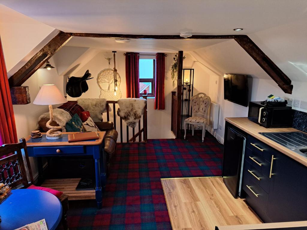 a kitchen and living room with a desk and a couch at Willow's Cottage in Edwinstowe