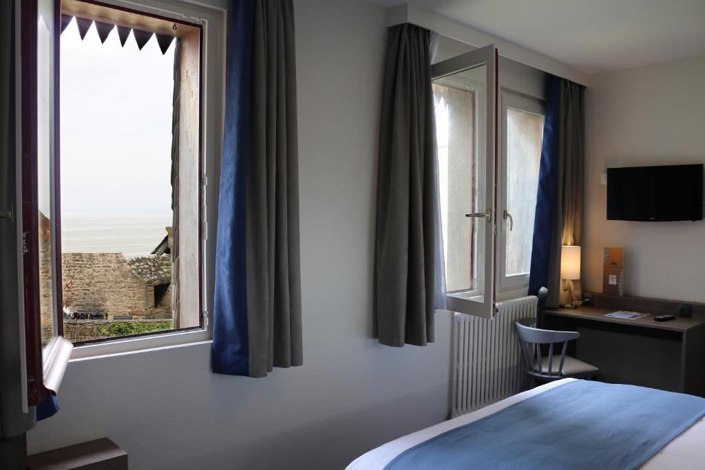 une chambre d'hôtel avec un lit et une fenêtre dans l'établissement Les Terrasses Poulard, au Mont-Saint-Michel