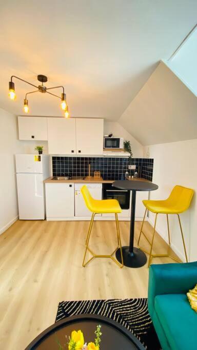 une cuisine avec une table et deux chaises jaunes dans l'établissement Appartements Cosy Le Havre, au Havre