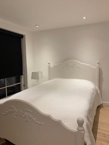 a white bed in a white bedroom with a window at Cozy place close to beautiful nature in Ballerup