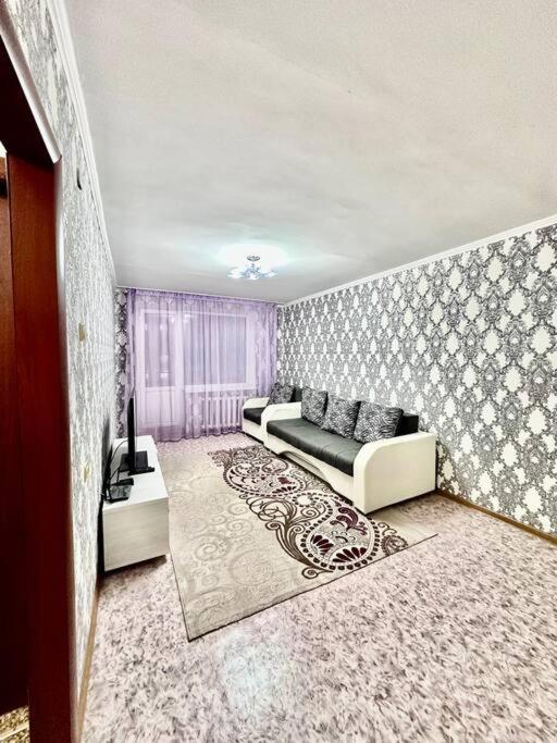 ein Wohnzimmer mit einem Sofa und einem Tisch in der Unterkunft Аренда с Самостоятельным Заездом in Pawlodar