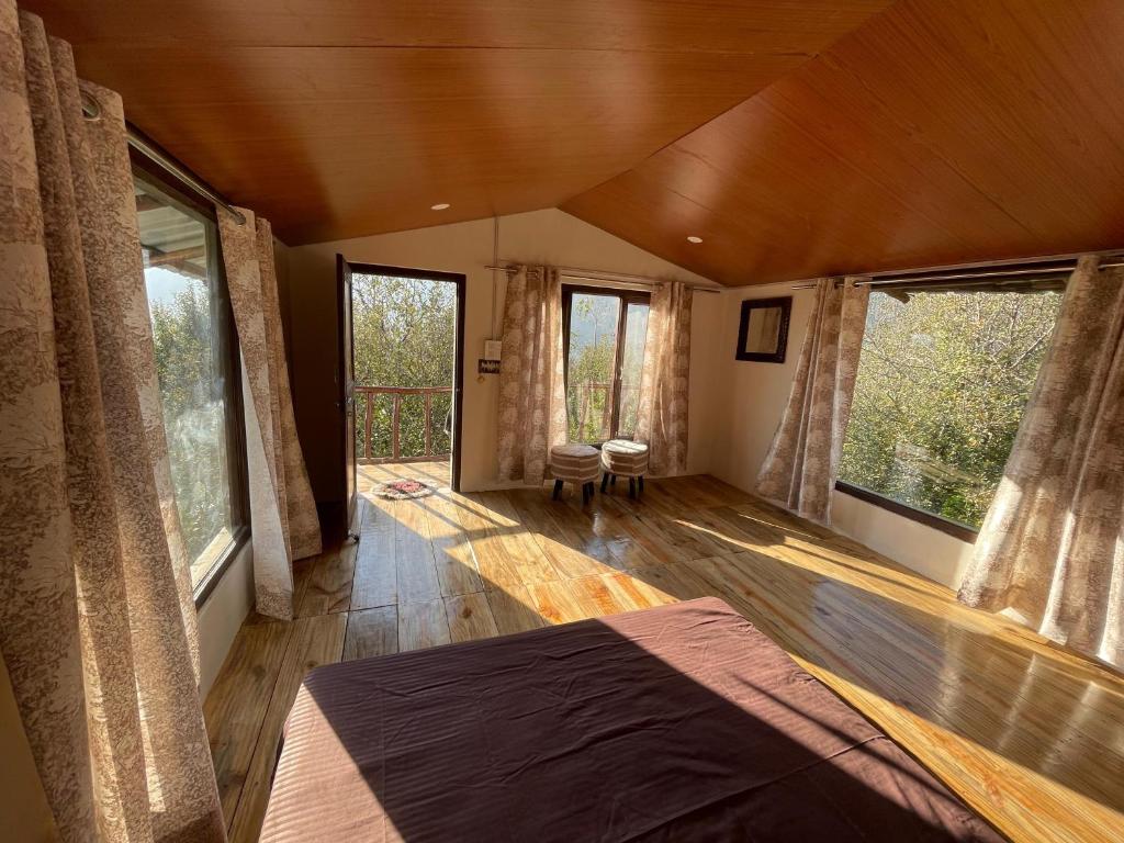 a bedroom with a bed in a room with windows at MANDAP COTTAGE & CAFE in Nagar