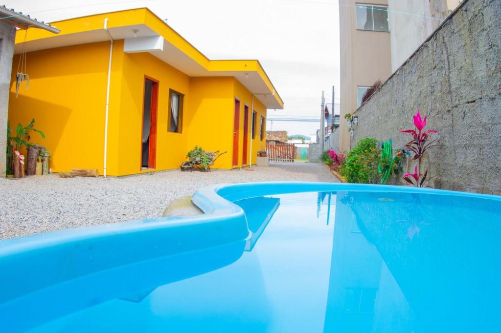 a swimming pool in front of a yellow house at Dom joaquim in Imbituba