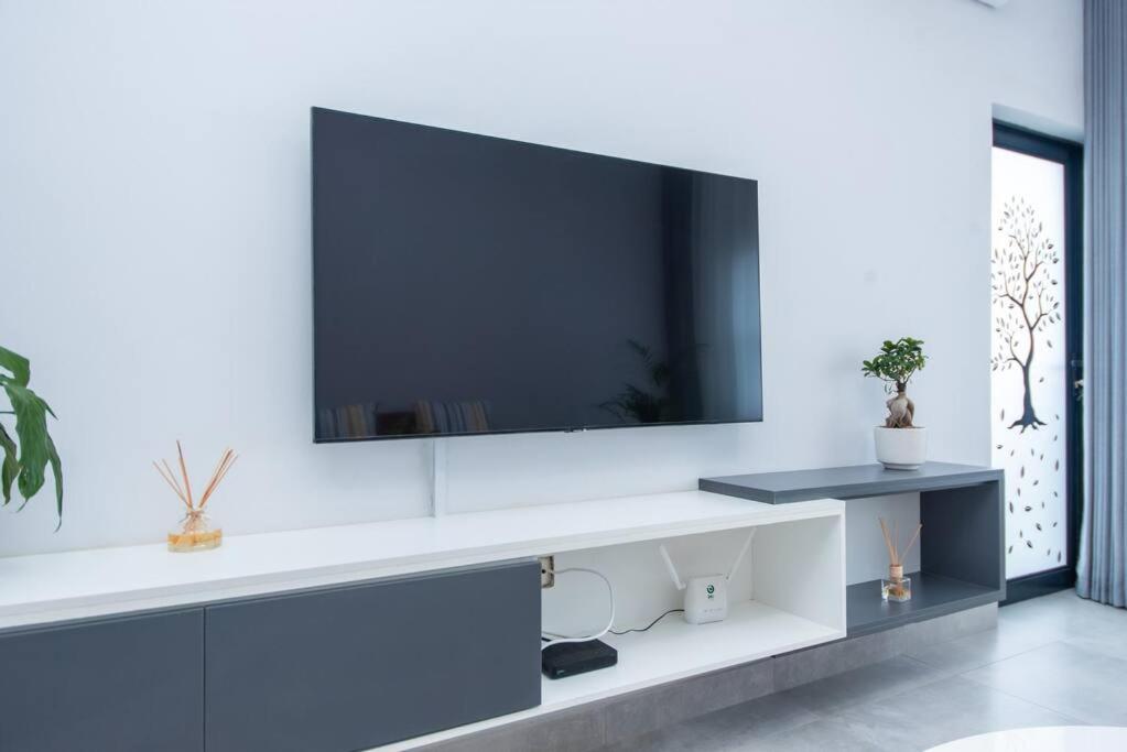 a living room with a tv on a white wall at Luxe Lumiere @ The Habitat Alpha in Gaborone