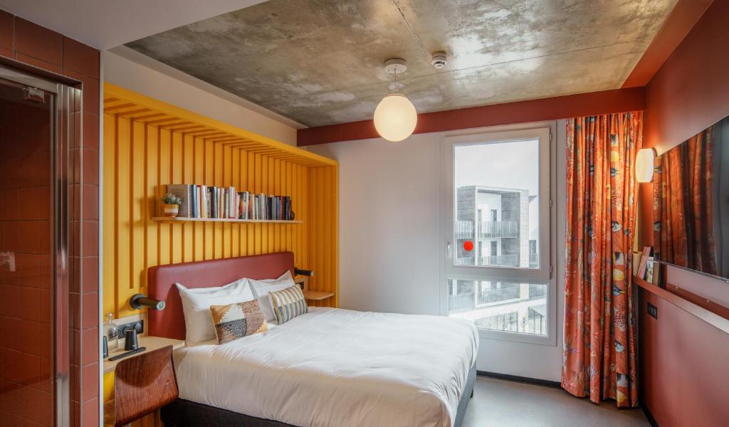 a bedroom with a bed and a large window at JOST Hôtel Le Havre Centre Gare in Le Havre