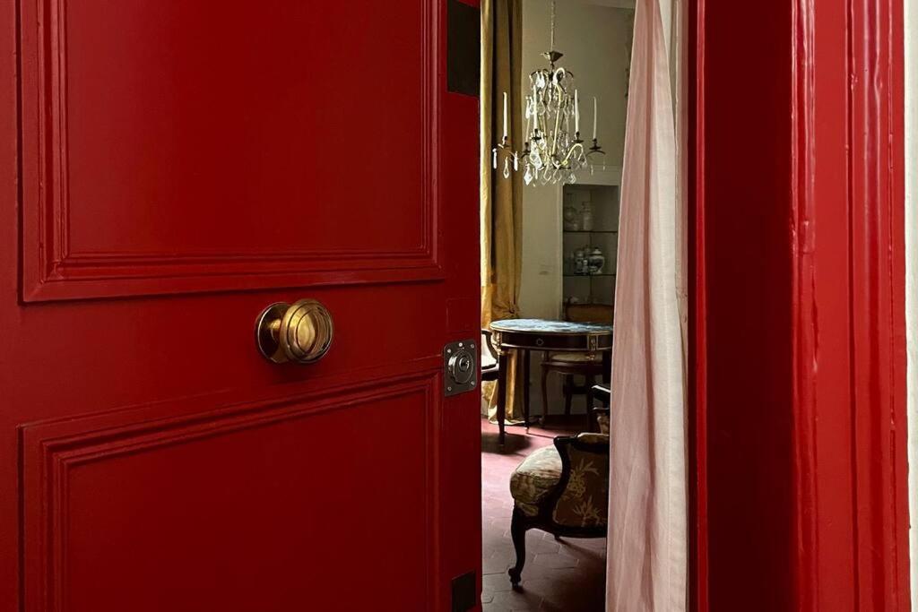 - une porte rouge dans une pièce avec une table dans l'établissement Studio de charme au cœur de l’Île St Louis, à Paris