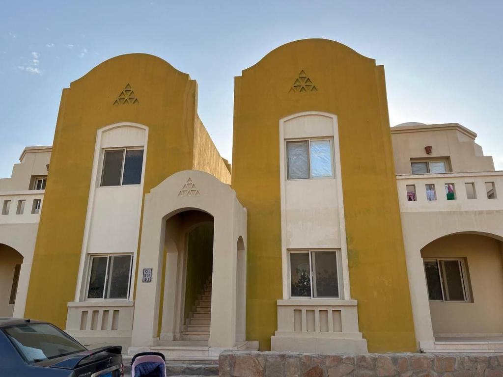 a yellow and white building with a car parked in front at Makady heights in Hurghada