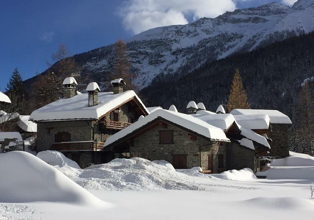 a building covered in snow with mountains in the background at Maison Chez Les Roset in Arvier