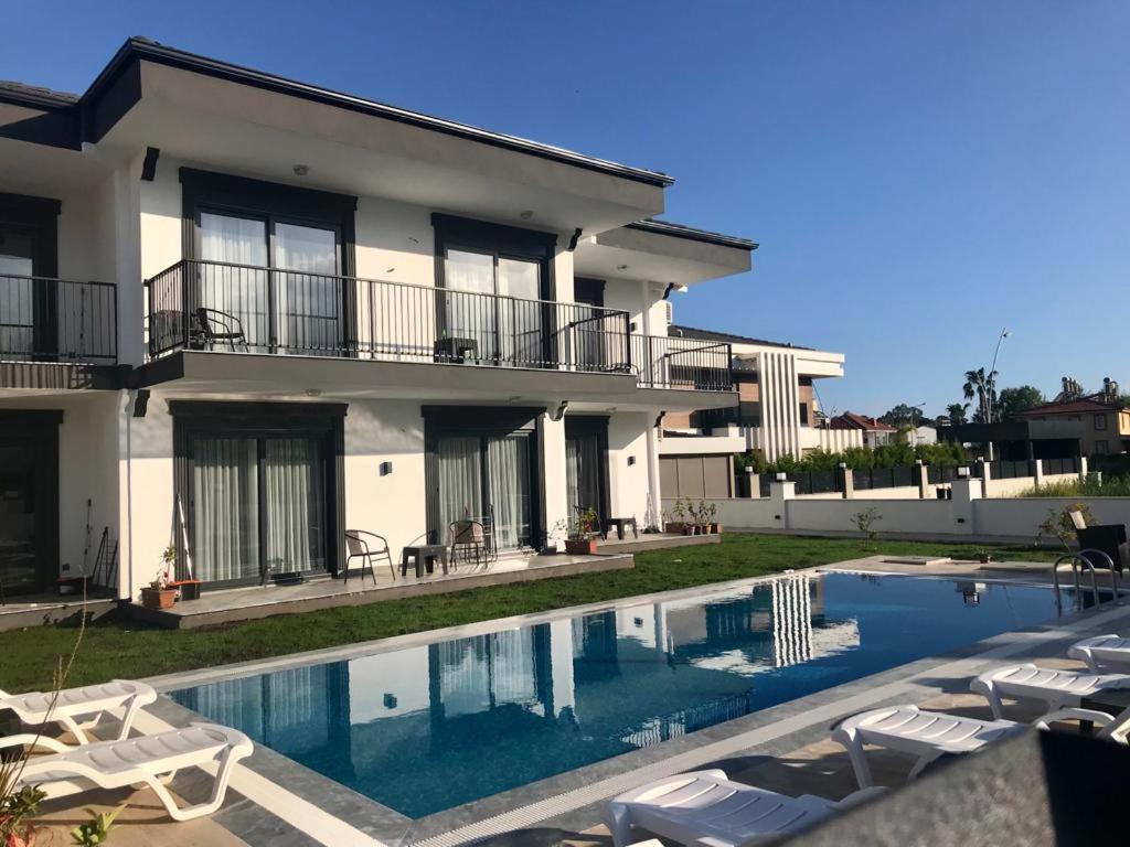 a villa with a swimming pool in front of a house at Tanem Suit in Antalya