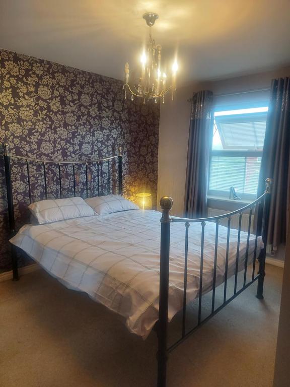 a bedroom with a large bed with a chandelier at Royal house in Ilkeston