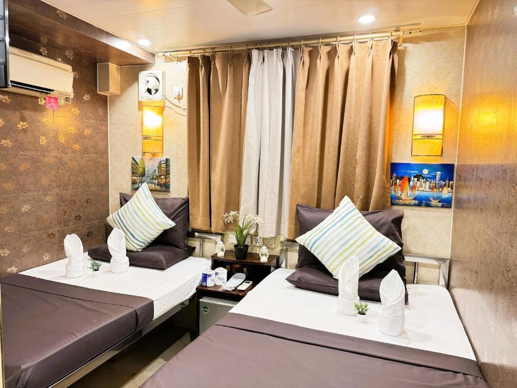 2 camas en una habitación pequeña con cortinas en New International Guest House en Hong Kong