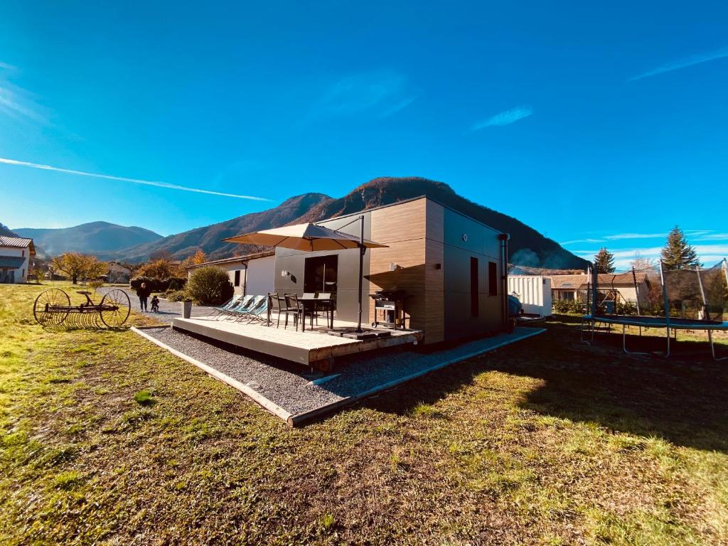 a small house in a field with a mountain in the background at Charmant logement entre Lac et Montagne in Rochebrune