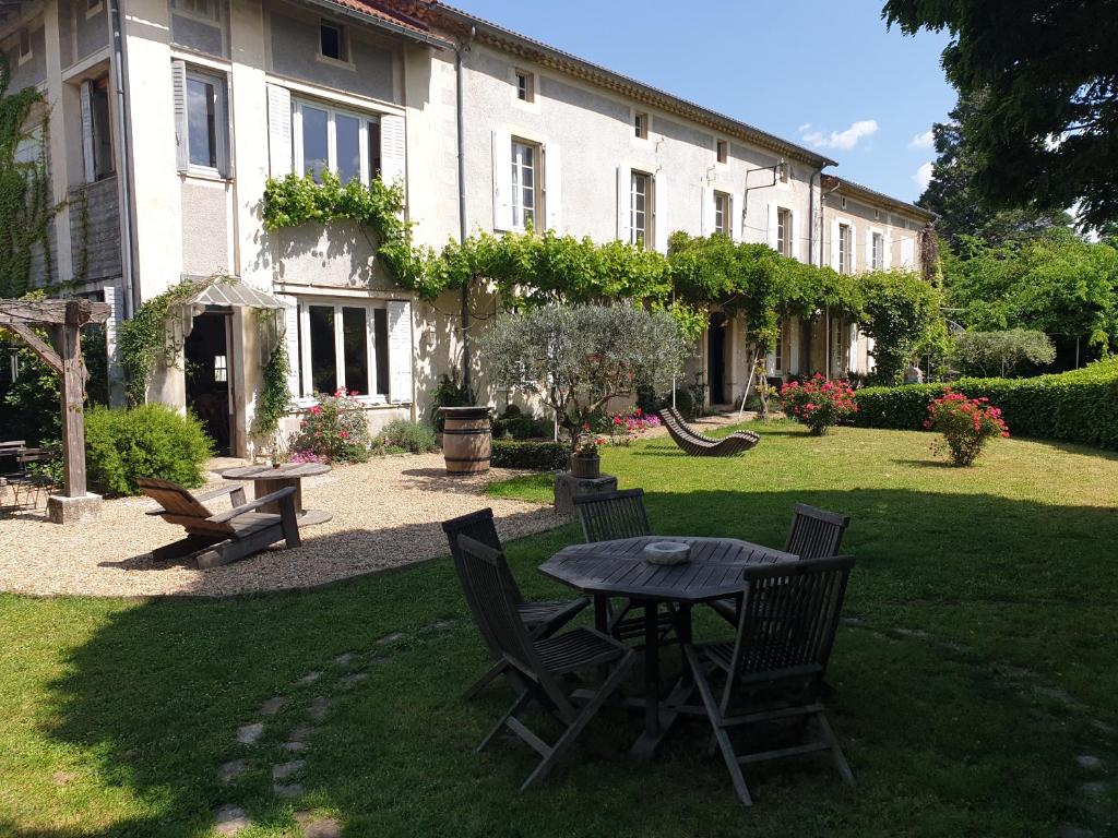 patio ze stołem i krzesłami przed budynkiem w obiekcie Au Ruisseau de Rose w mieście Saint-Jean-du-Gard